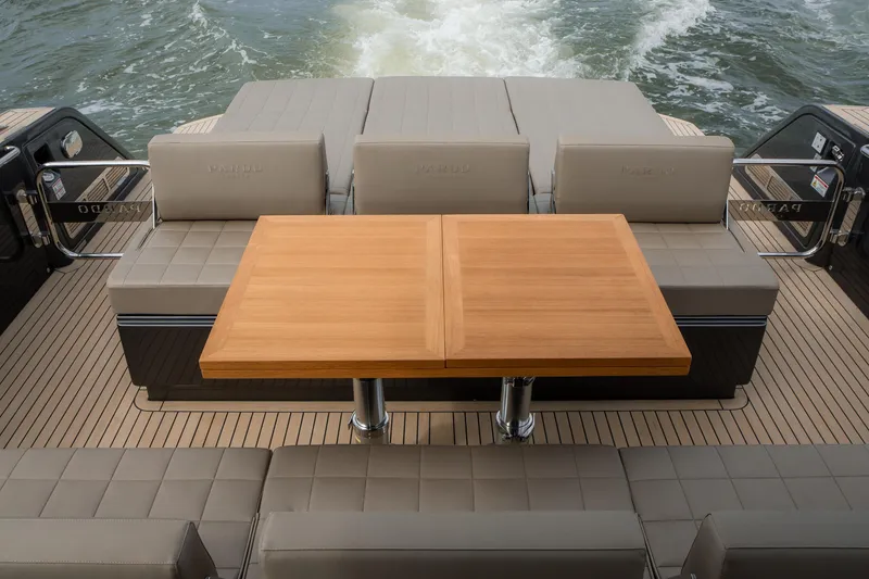 Slide: The Image of 2024 Pardo Yachts P43 deck with elegant seating and wooden table, cruising on water. - 12