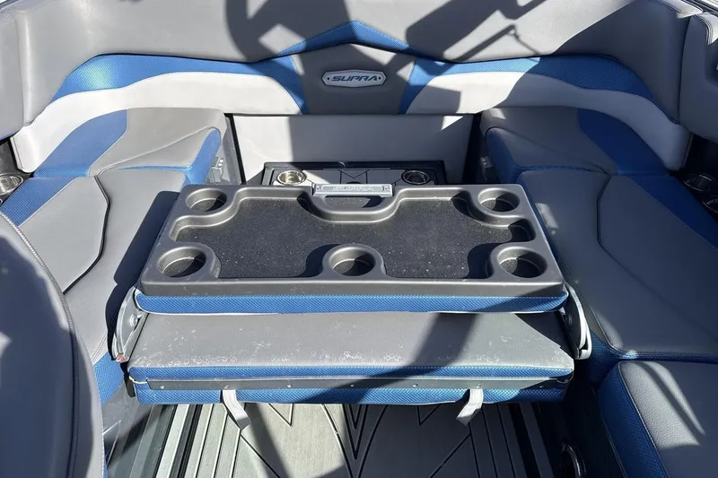 Slide: The Image of 2019 Supra SR boat interior with blue and gray seating and a foldable table. - 23