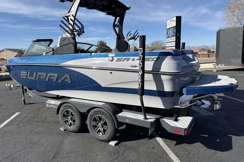 Slide: The Image of 2019 Supra SR boat on trailer, blue and white design, parked outdoors. - 3