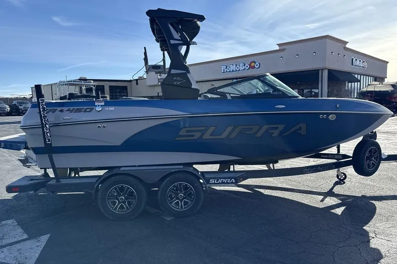Slide: The Image of 2019 Supra SR boat on trailer in parking lot, blue and gray design. - 6