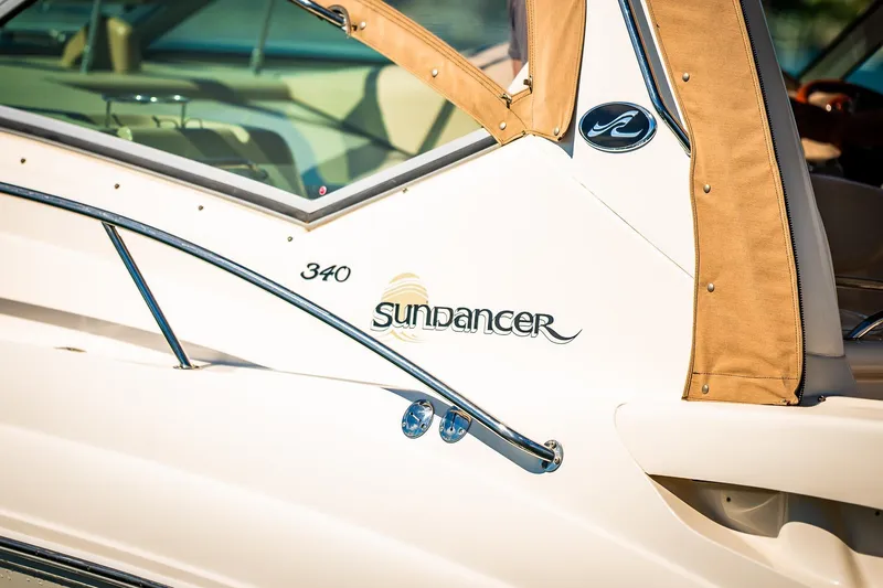 Slide: The Image of 2003 Sea Ray 340 Sundancer boat with tan canopy and sleek design. - 2
