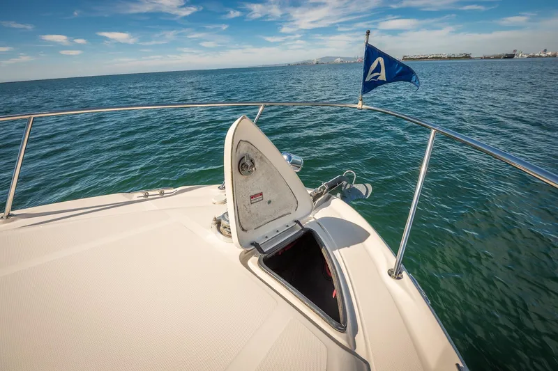 Slide: The Image of 2003 Sea Ray 340 Sundancer bow with open hatch and blue flag on calm sea. - 28