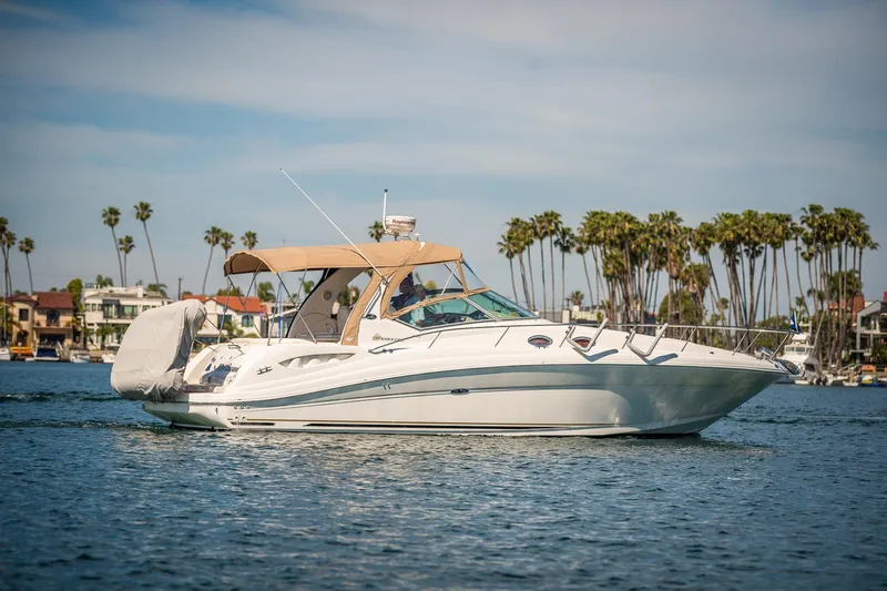 Slide: The Image of 2003 Sea Ray 340 Sundancer yacht cruising on a sunny day with palm trees in background. - 32