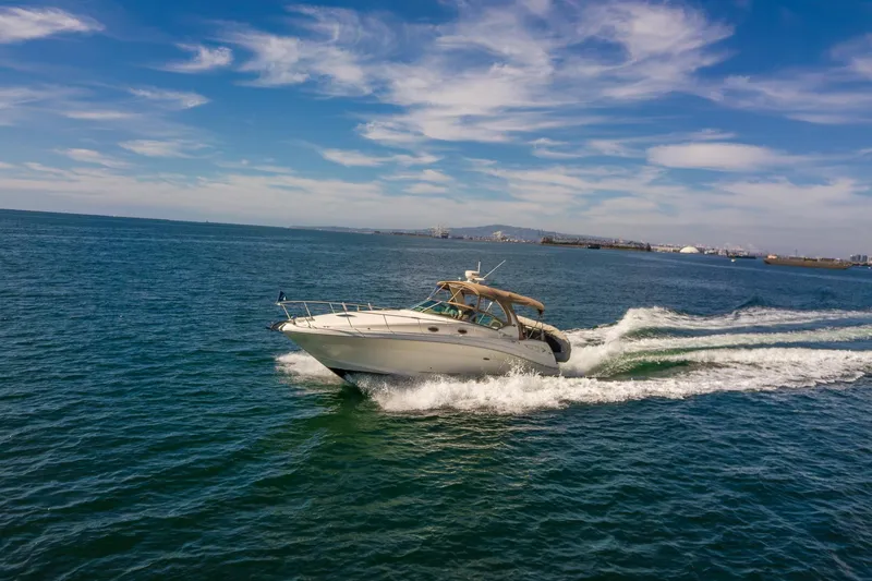Slide: The Image of 2003 Sea Ray 340 Sundancer cruising on open water under a clear blue sky. - 34