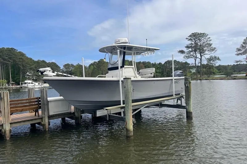 Slide: The Image of 2021 Parker 2300 DV Center Console boat docked on a lift by a scenic lake. - 3