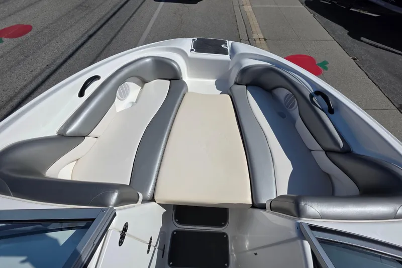 Slide: The Image of 2009 Yamaha AR210 boat interior with gray and white seating, docked on a sunny day. - 22