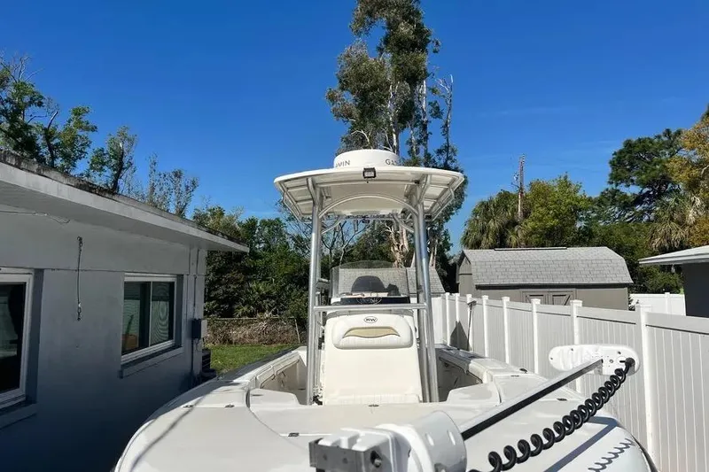 Slide: The Image of 2010 Key West 246 Bay Reef boat parked beside a house under clear blue sky. - 23