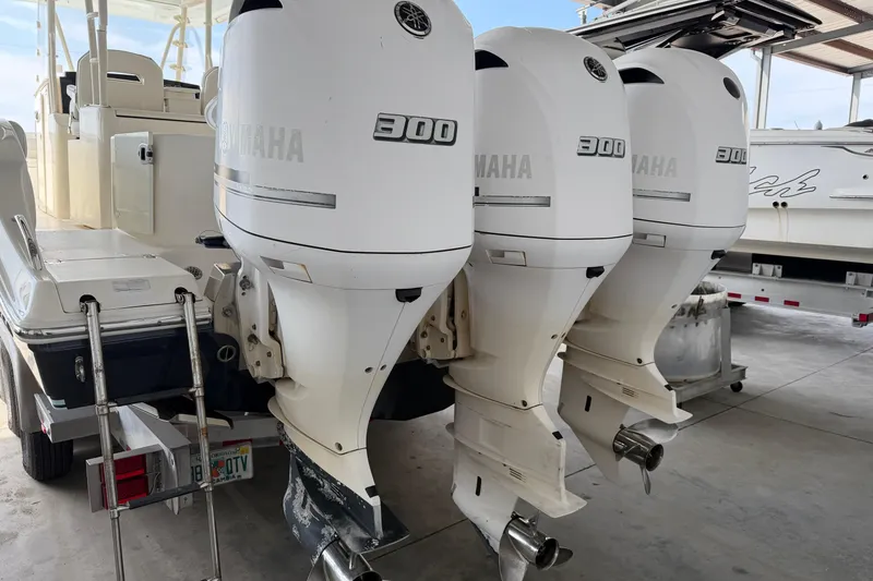 Slide: The Image of 2015 Cobia 344 Center Console with triple Yamaha 300 engines in a marina. - 13