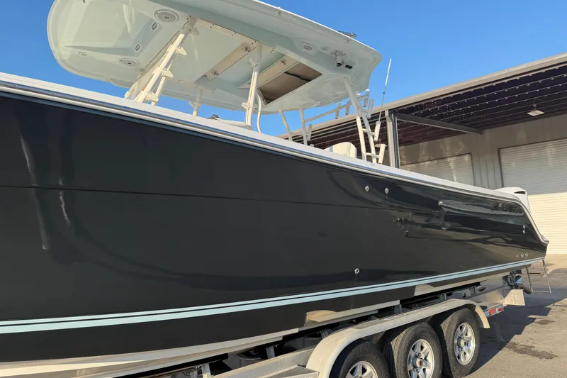 Slide: The Image of 2015 Cobia 344 Center Console boat on trailer, black hull, outdoor setting. - 158