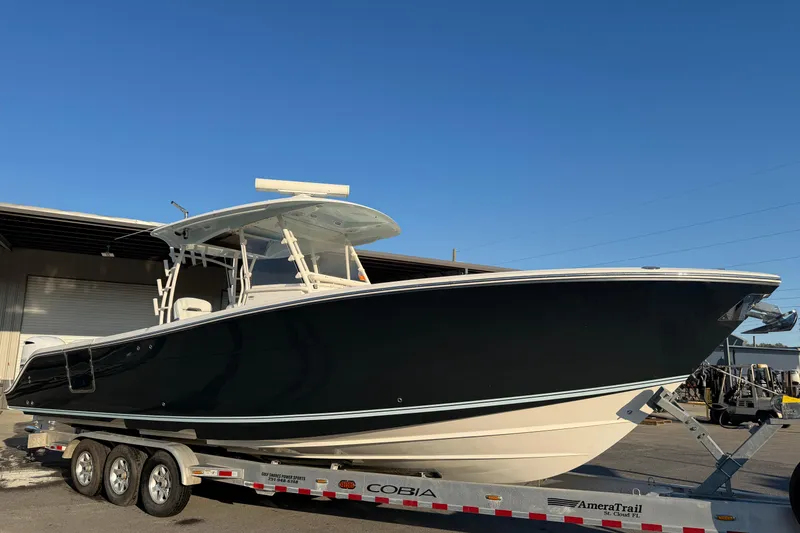 Slide: The Image of 2015 Cobia 344 Center Console boat on trailer, parked outdoors under clear blue sky. - 161