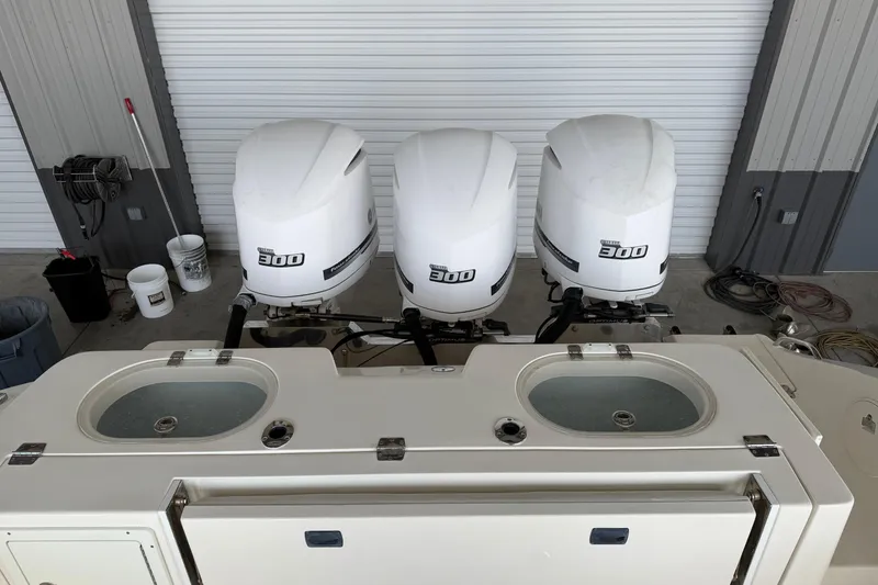 Slide: The Image of 2015 Cobia 344 Center Console with triple 300 horsepower engines in a garage setting. - 20
