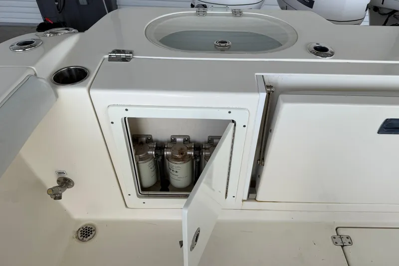 Slide: The Image of 2015 Cobia 344 Center Console boat with open storage compartment and visible filters. - 22