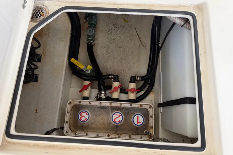 Slide: The Image of 2015 Cobia 344 Center Console boat compartment with valves and hoses. - 27