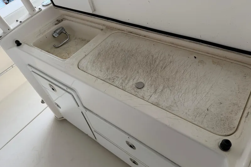 Slide: The Image of 2015 Cobia 344 Center Console boat sink and cutting board area, showing wear and scratches. - 34
