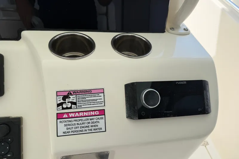 Slide: The Image of 2015 Cobia 344 Center Console dashboard with cup holders, warning labels, and Fusion audio system. - 44
