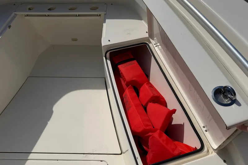 Slide: The Image of Storage compartment with red life jackets on a 2015 Cobia 344 Center Console boat. - 88