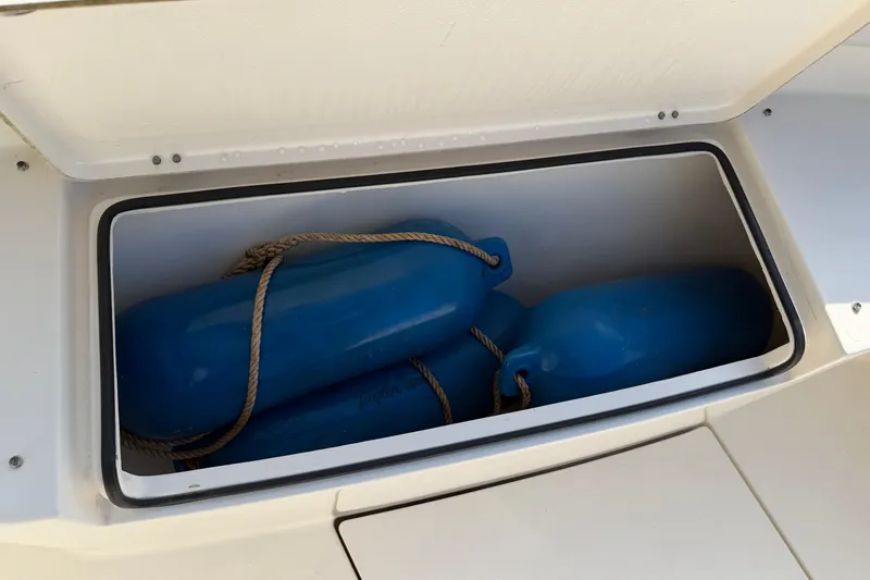 Slide: The Image of Storage compartment with blue fenders on a 2015 Cobia 344 Center Console boat. - 89