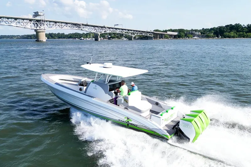 Slide: The Image of 2023 Statement 350 Open boat cruising on water near a bridge, sunny day. - 1