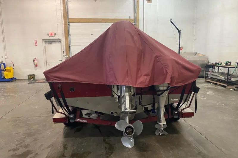 Slide: The Image of 2001 Lund 1900 Pro-V SE boat with maroon cover in a garage setting. - 2