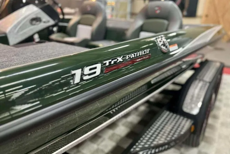 Slide: The Image of 2026 Triton 19 TrX Patriot boat, close-up of sleek design and logo. - 18
