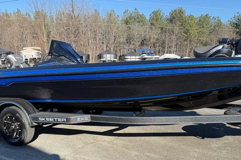 Slide: The Image of 2026 Skeeter ZXE21 boat on trailer, blue and black design, parked outdoors. - 22