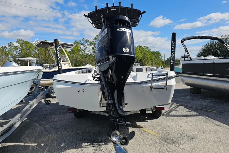 Slide: The Image of 2025 Savannah 220 IS boat with Suzuki 200 engine, parked outdoors under blue sky. - 1