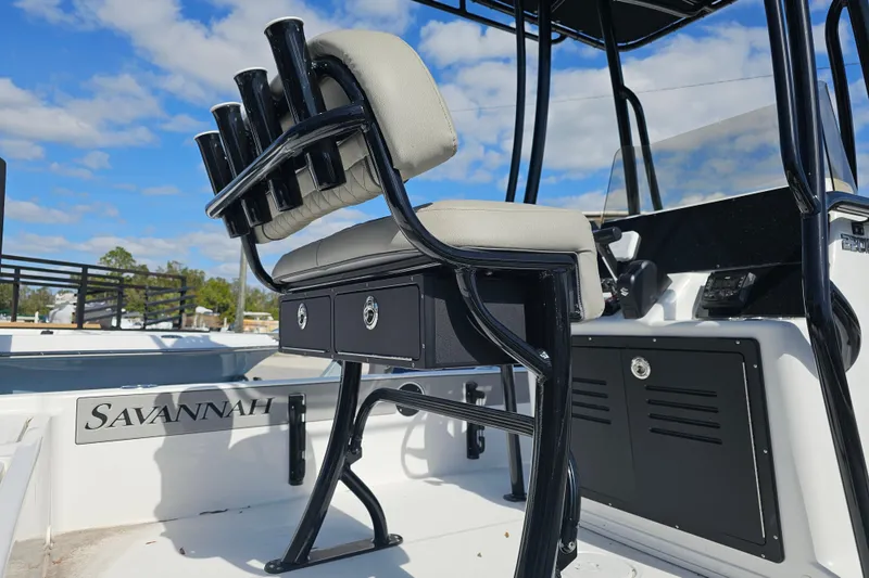 Slide: The Image of 2025 Savannah 220 IS boat interior with cushioned seating and rod holders under a blue sky. - 3