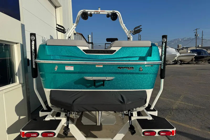Slide: The Image of 2026 Moomba Tykon boat with teal exterior, parked outdoors, featuring Raptor engine branding. - 4
