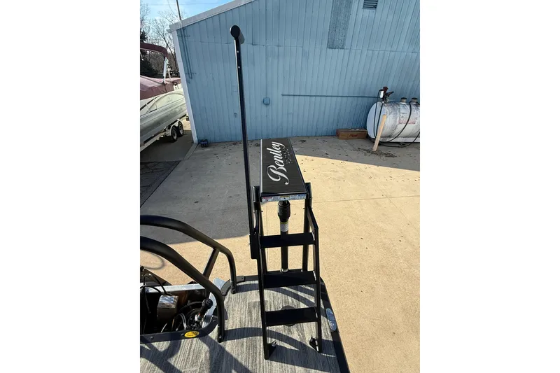 Slide: The Image of 2026 Bentley Pontoons Legacy 243 Navigator ladder on dock, with blue building background. - 28