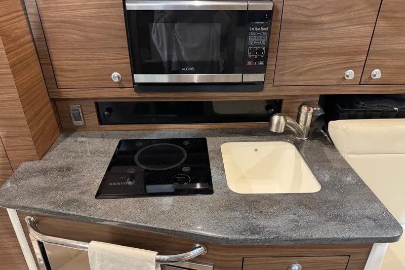 Slide: The Image of 2022 Boston Whaler 325 Conquest Pilothouse kitchen with microwave, stovetop, and sink. - 10