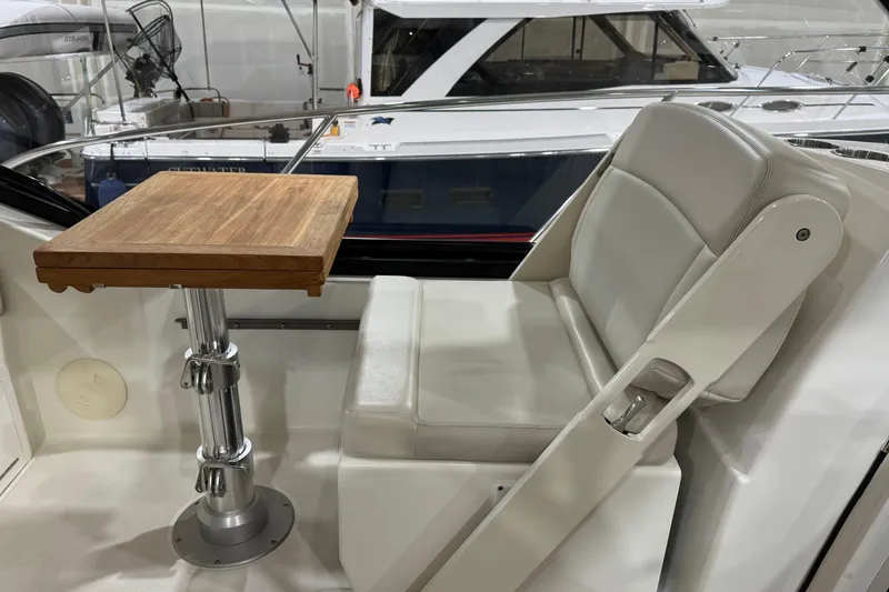 Slide: The Image of 2022 Boston Whaler 325 Conquest Pilothouse interior with seating and wooden table. - 11