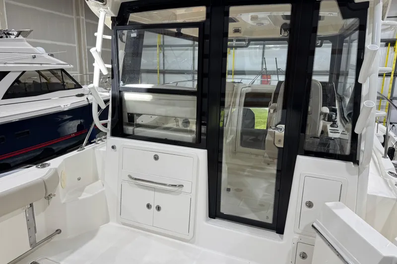 Slide: The Image of 2022 Boston Whaler 325 Conquest Pilothouse interior with glass doors and storage compartments. - 2