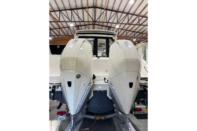 Slide: The Image of 2022 Boston Whaler 325 Conquest Pilothouse with dual outboard engines in a boatyard. - 4