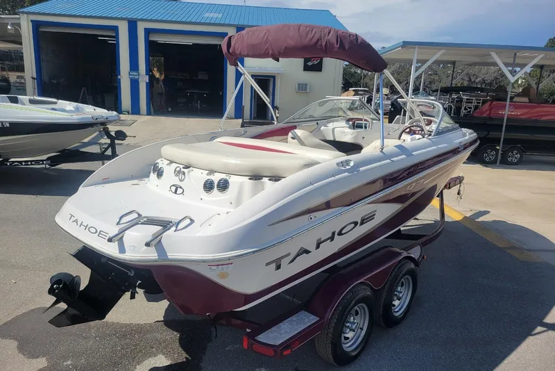 Slide: The Image of 2014 Tahoe Q7i boat on trailer, parked near blue-roofed building. - 3