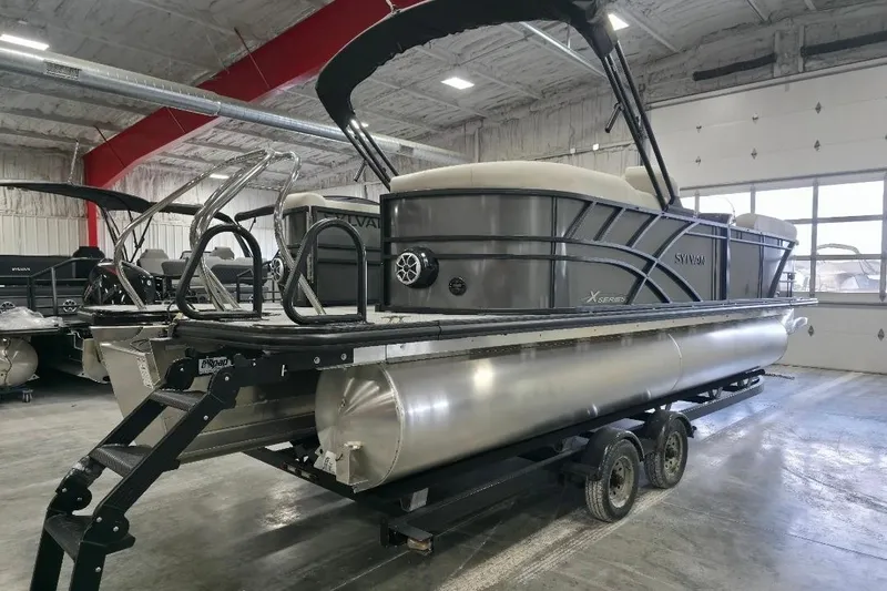 Slide: The Image of 2026 Sylvan Mirage X5 pontoon boat in a showroom on a trailer. - 4