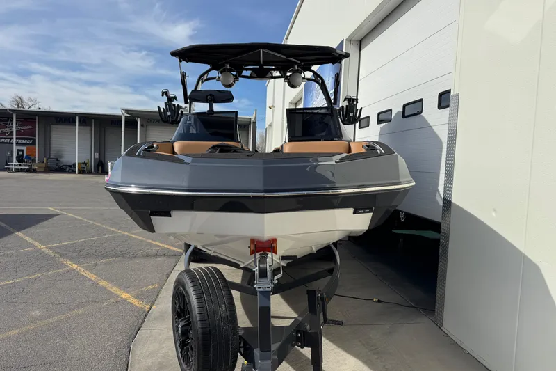 Slide: The Image of 2026 Moomba Tykon boat on trailer, parked outside a garage under a clear sky. - 4