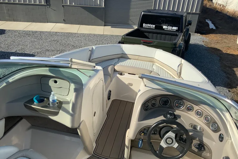 Slide: The Image of 2007 Bryant 206 boat interior with dashboard and seating, parked near a black truck. - 7