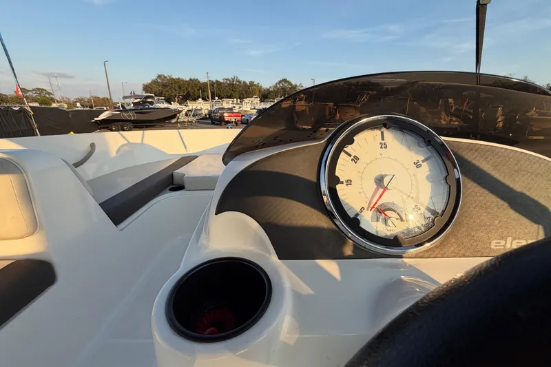 Slide: The Image of 2019 Bayliner Element E16 dashboard with speedometer, cup holder, and outdoor marina view. - 20