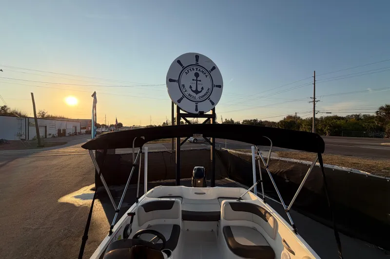 Slide: The Image of 2019 Bayliner Element E16 boat at sunset with a canopy and sign in the background. - 43
