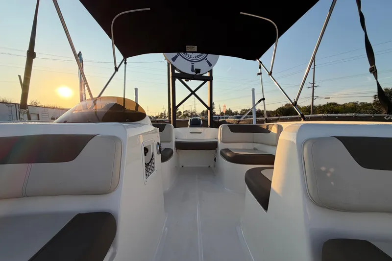 Slide: The Image of 2019 Bayliner Element E16 boat interior with seating, canopy, and sunset view. - 44