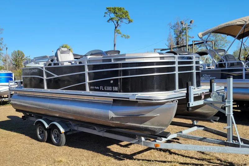 Slide: The Image of 2020 Crestliner 200 Rally DX CS pontoon boat on trailer, parked outdoors. - 1