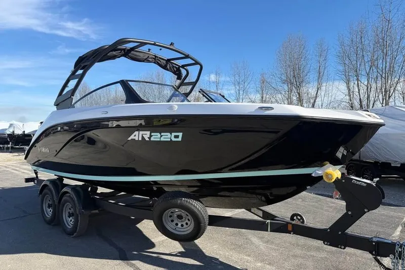 Slide: The Image of 2026 Yamaha Boats AR220 on trailer, sleek black design under clear blue sky. - 2