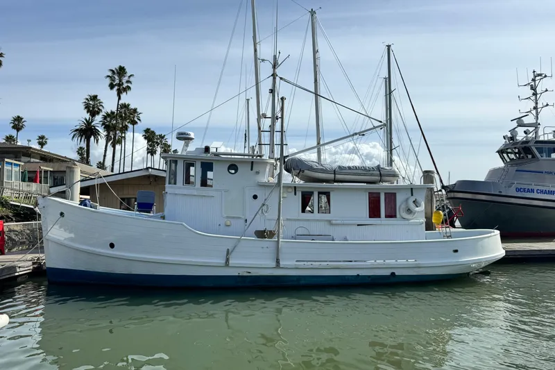 The Image of Historic 1918 Peterson Tugboat docked in a marina, surrounded by palm trees and other vessels. - 1