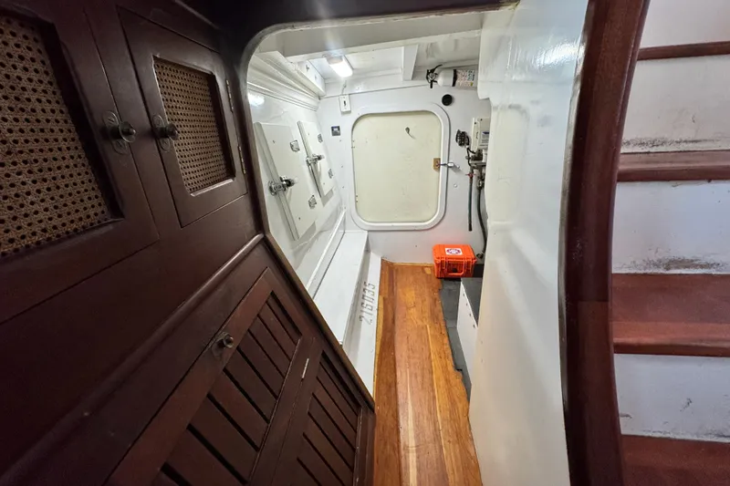 Slide: The Image of Interior of 1918 Peterson Tugboat, featuring wooden cabinets and stairs, with a white hatch door. - 12