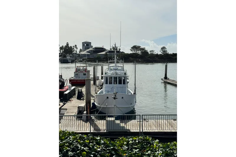 Slide: The Image of Historic 1918 Peterson Tugboat docked at a marina, surrounded by calm waters and greenery. - 24
