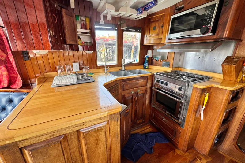 Slide: The Image of Wooden kitchen interior of 1918 Peterson Tug with stove, sink, and microwave. - 5