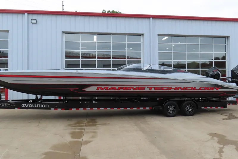 Slide: The Image of 2025 MTI 390X powerboat on trailer, sleek design, parked outside a garage. - 2