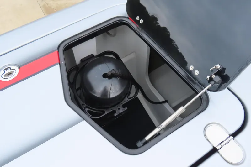 Slide: The Image of Open storage compartment in 2025 MTI 390X boat, featuring a black lid and hydraulic support. - 22