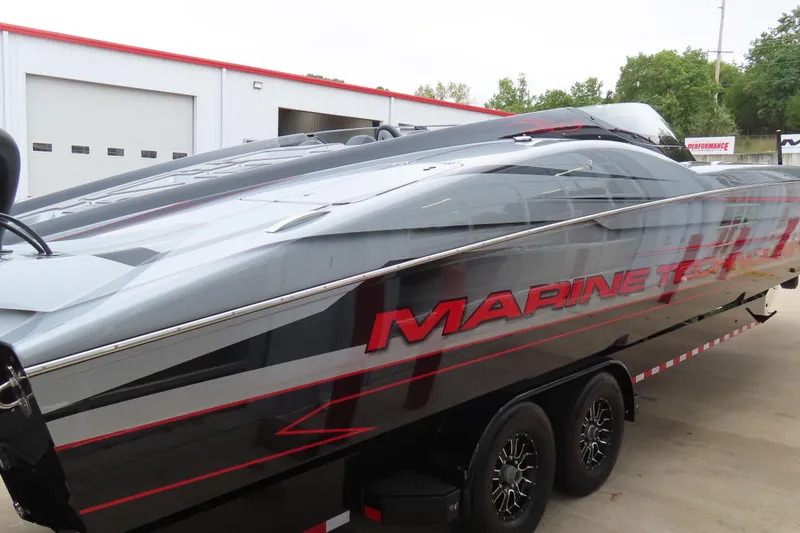Slide: The Image of 2025 MTI 390X powerboat with sleek design, parked on a trailer outside a garage. - 9