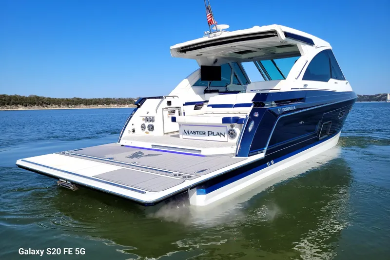 Slide: The Image of 2023 Formula 380 Super Sport Crossover I/O boat on calm water, rear view. - 11